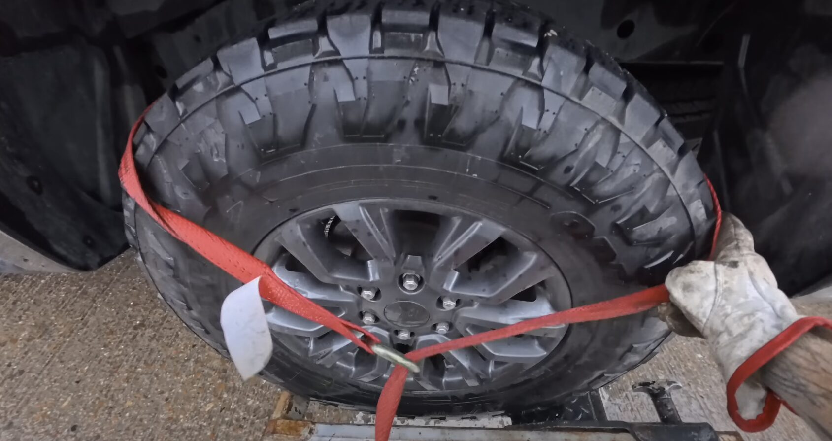 Professional roadside assistance - tire replacement and emergency repairs Roadside assistance technician securing vehicle tire with emergency straps