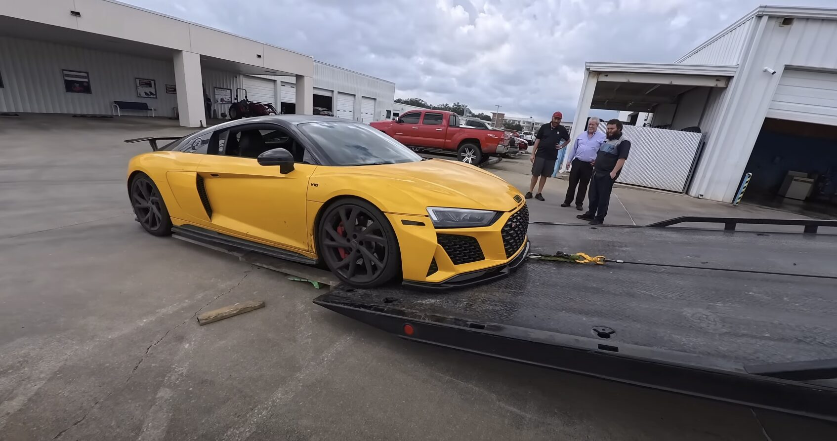 Luxury vehicle towing - flatbed service for high-performance cars Yellow sports car being loaded onto professional flatbed tow truck